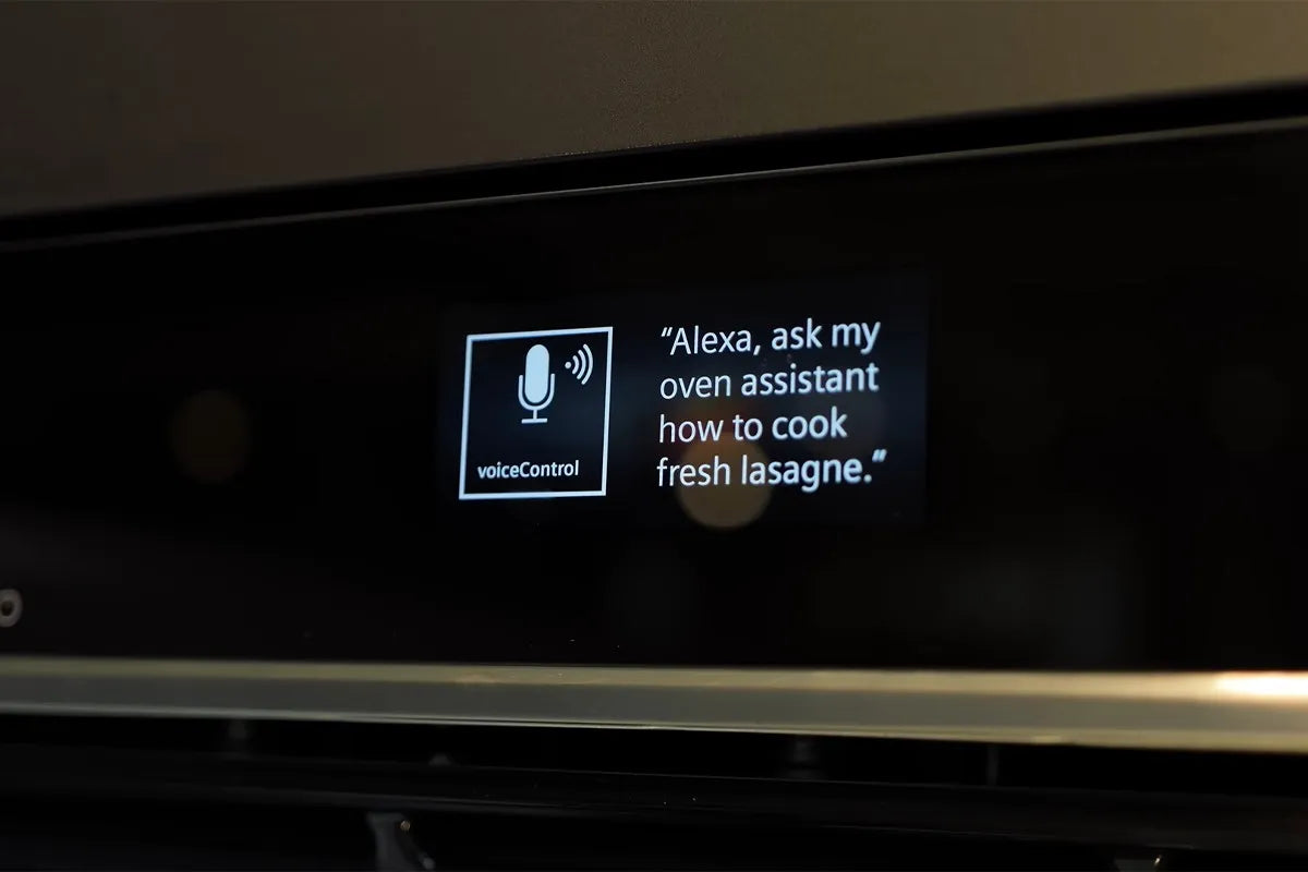 Een display van een Siemens oven waarop een melding staat met spraakbediening: “Alexa, ask my oven assistant how to cook fresh lasagne.”; links van de tekst staat een pictogram van een microfoon met de aanduiding “voiceControl”.