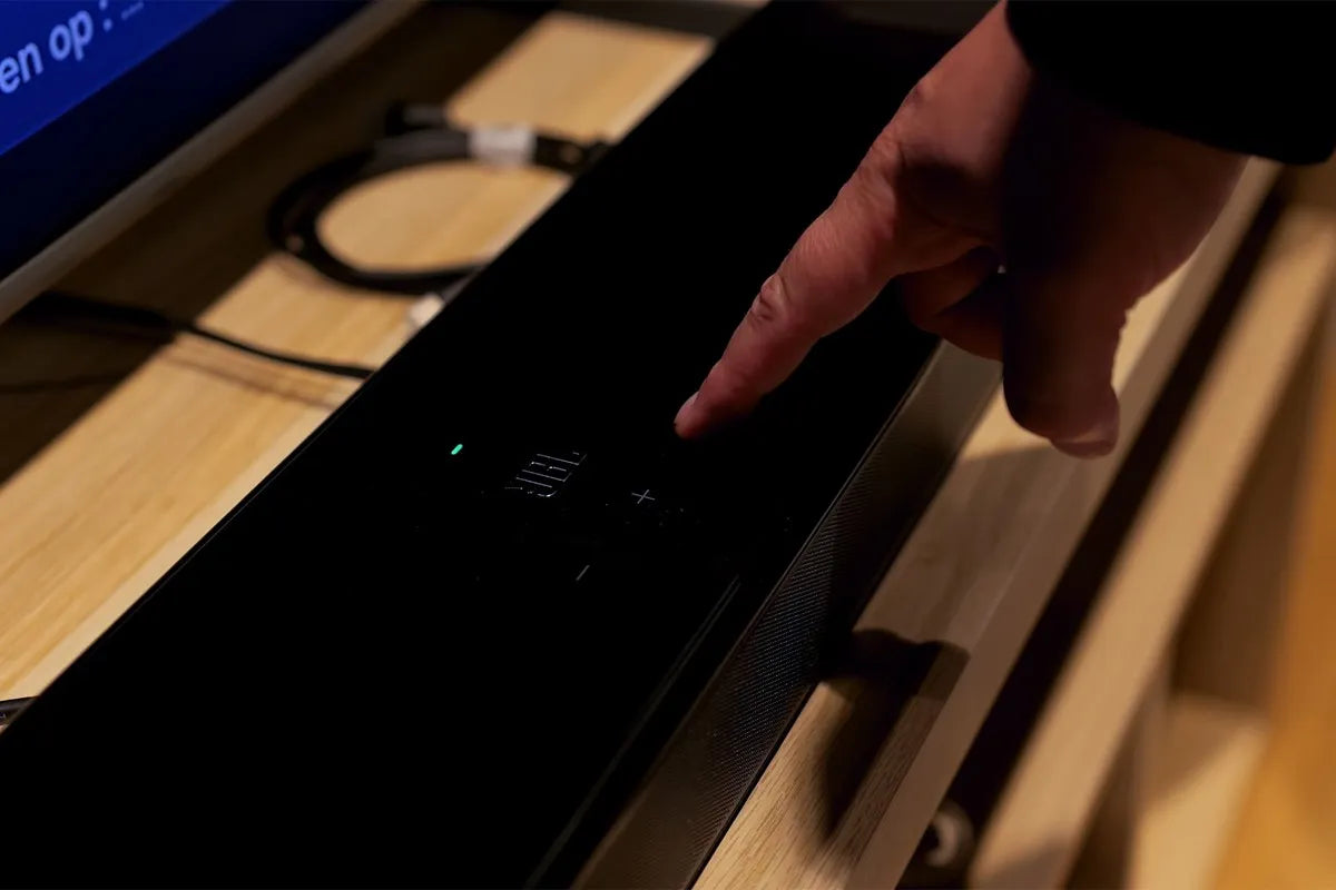 Een persoon bedient de JBL 1300MKII door met de wijsvinger op de aanraakgevoelige knoppen aan de bovenzijde te drukken.