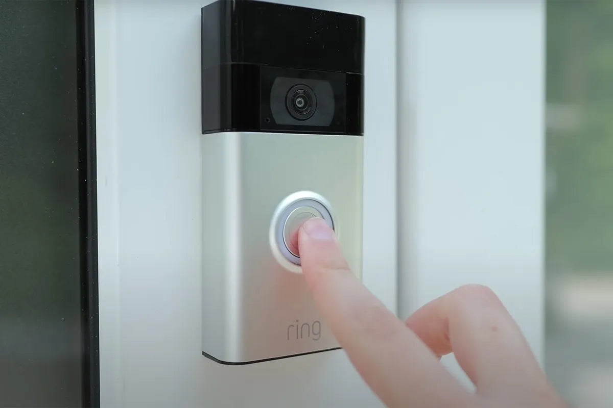 Ring videodeurbel aan de deurpost wordt ingedrukt met wijsvinger