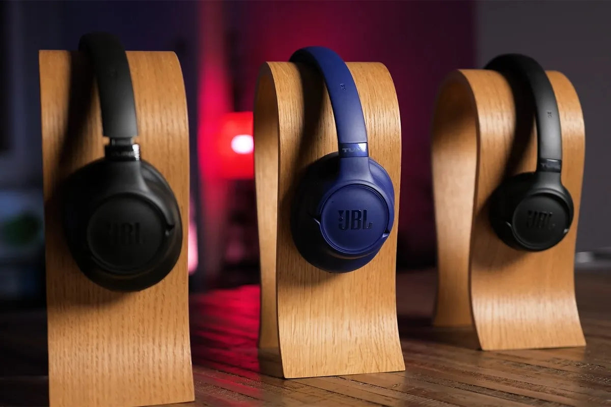 Drie koptelefoons uit de JBL Tune-serie op een houten standaard.