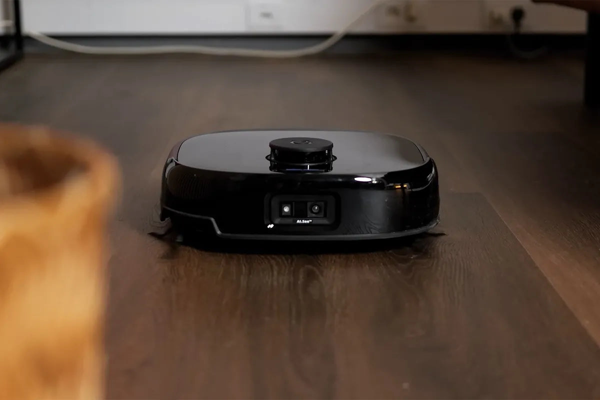 De Eufy Omni E28 rijdt over een donker houten vloer. Aan de voorzijde is een dubbele camera zichtbaar.