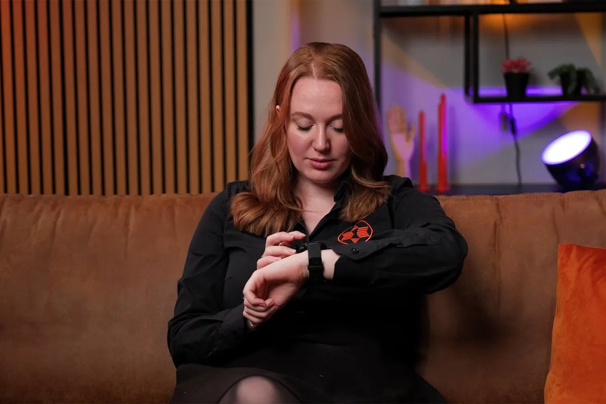 Presentatrice op de bank kijkend naar de Garmin Vivoactive 6 smartwatch om haar pols terwijl ze door het menu scrolt